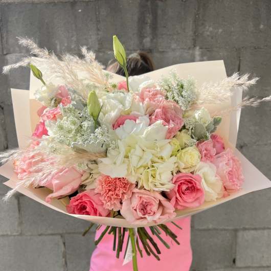 Large bouquet of pink and white flowers wrapped in pale paper