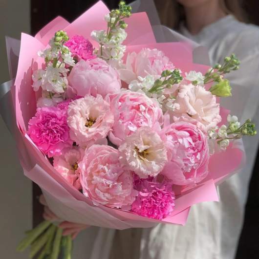 Pink bouquet of peonies, carnations, and white blooms wrapped in pink paper