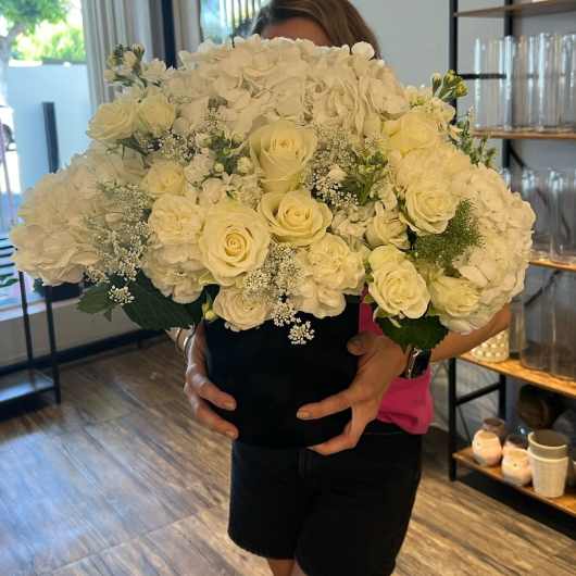 Large white floral arrangement in a black box