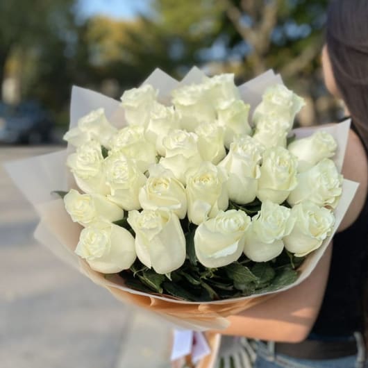 Bouquet of white roses wrapped in pale paper