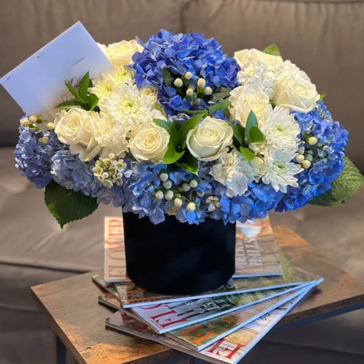 Blue and white floral arrangement in a black vase