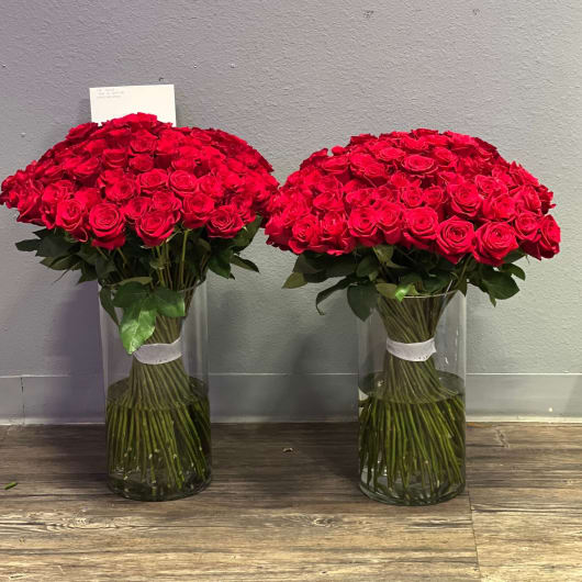 Two large bouquets of red roses in clear glass vases
