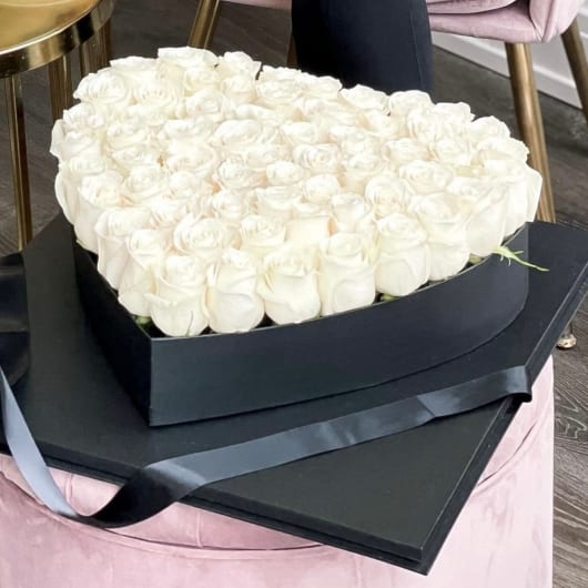 Heart-shaped box filled with white roses and black ribbon