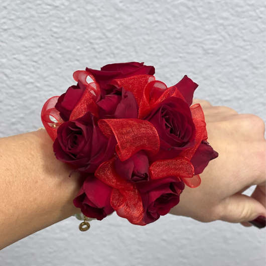 Red rose wrist corsage with sheer ribbon on a person's wrist