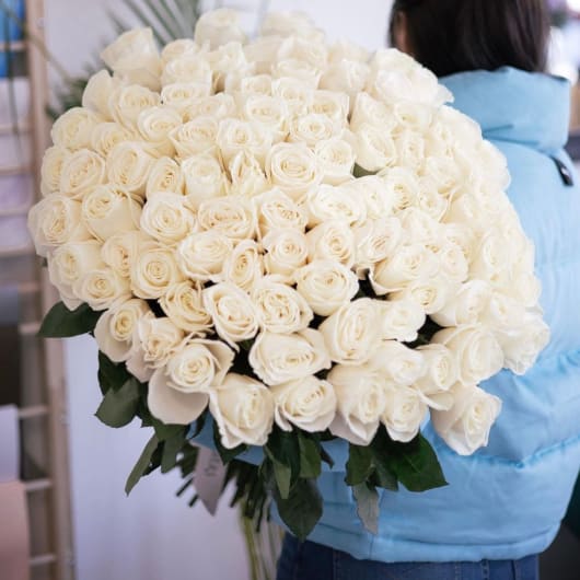 Large bouquet of white roses held by a person in a blue jacket