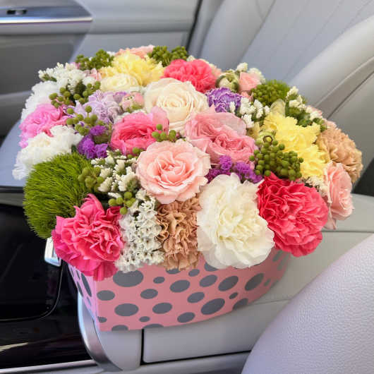 Mixed bouquet of pastel roses and carnations in a pink polka-dot box