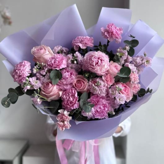 Pink bouquet of roses and carnations wrapped in lavender paper