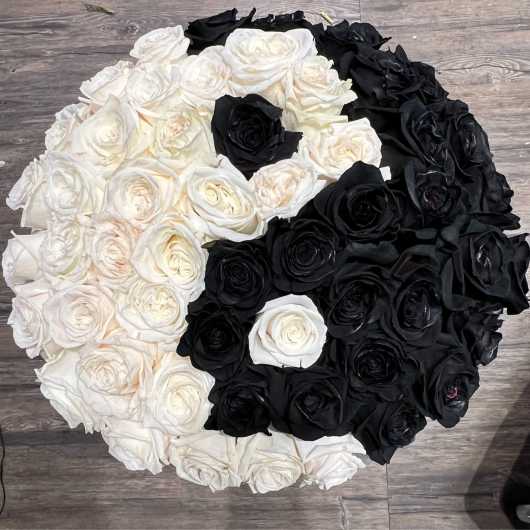 Round arrangement of white and black roses on a wood floor