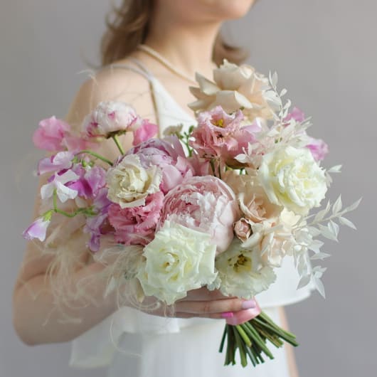 Woman holding a pastel bouquet of pink and white flowers