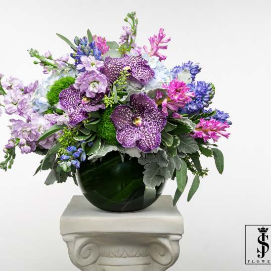 Mixed purple and blue flowers arranged in a dark glass vase