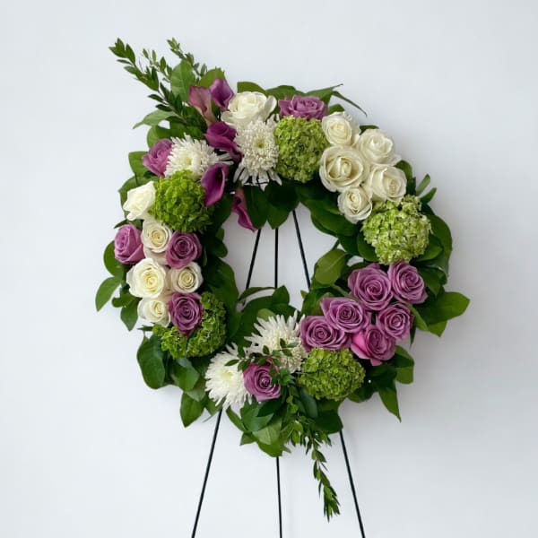 Floral wreath with purple and white roses on a black stand