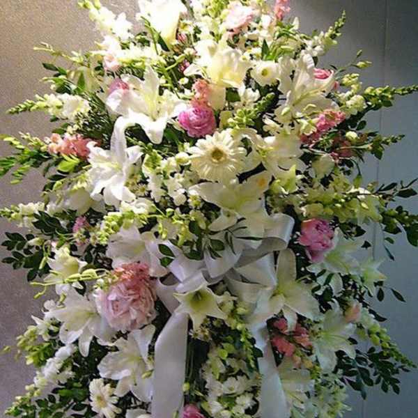 Tall white and pink standing spray of lilies, daisies, and roses with flowing white ribbon