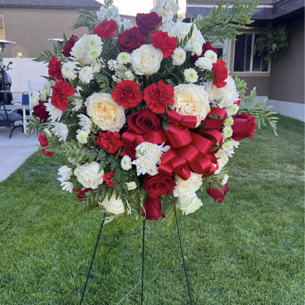 Large red and white rose wreath on a stand with a red bow