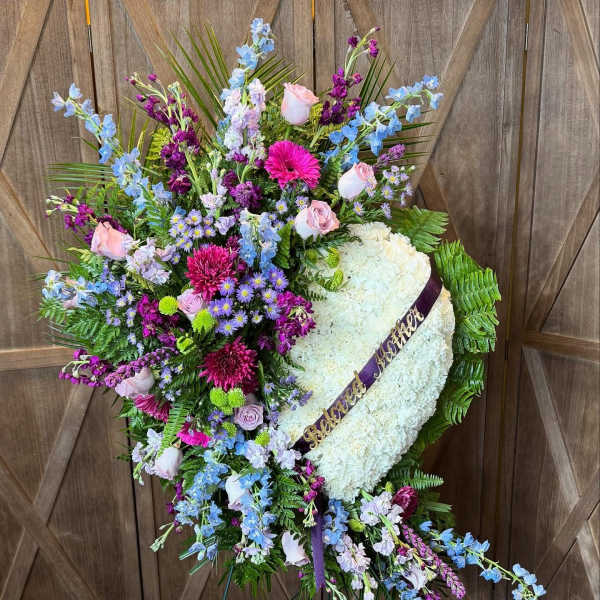 Heart-shaped funeral wreath with white flowers and pastel blooms