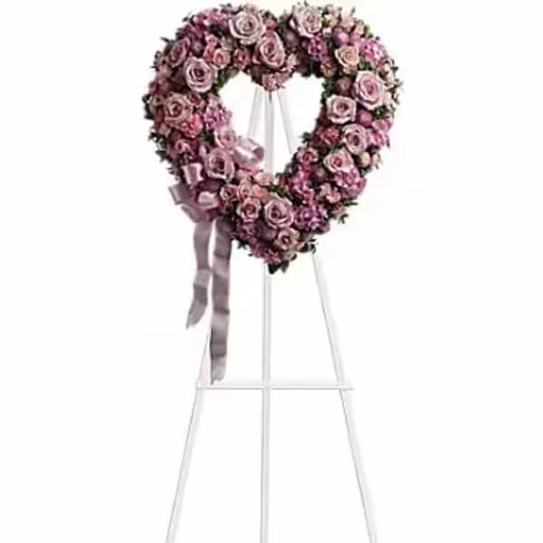 Heart-shaped pink rose wreath on a white easel with ribbon