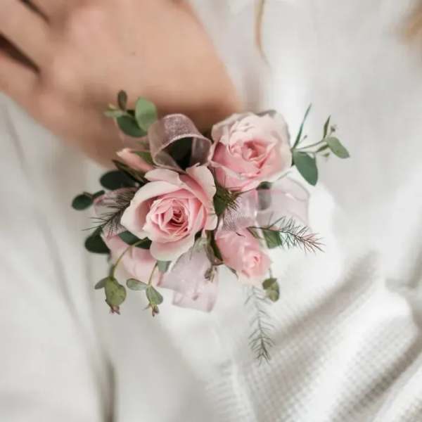 Small pink rose corsage with ribbon and greenery