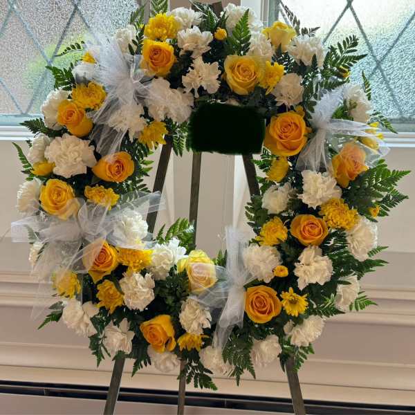 Yellow and white floral wreath with tulle bows on an easel