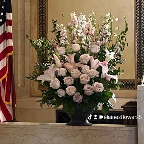 Large pastel floral arrangement in a dark urn vase