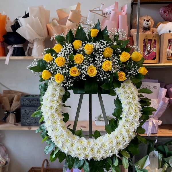 Yellow roses and white chrysanthemum wreath on an easel