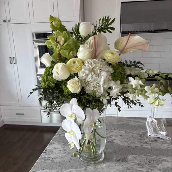 White and green floral arrangement in a clear glass vase