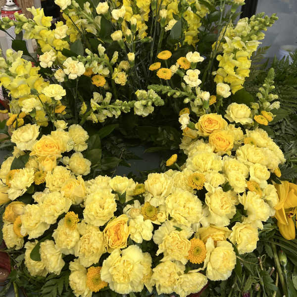 Large yellow floral wreath with roses, carnations, and snapdragons