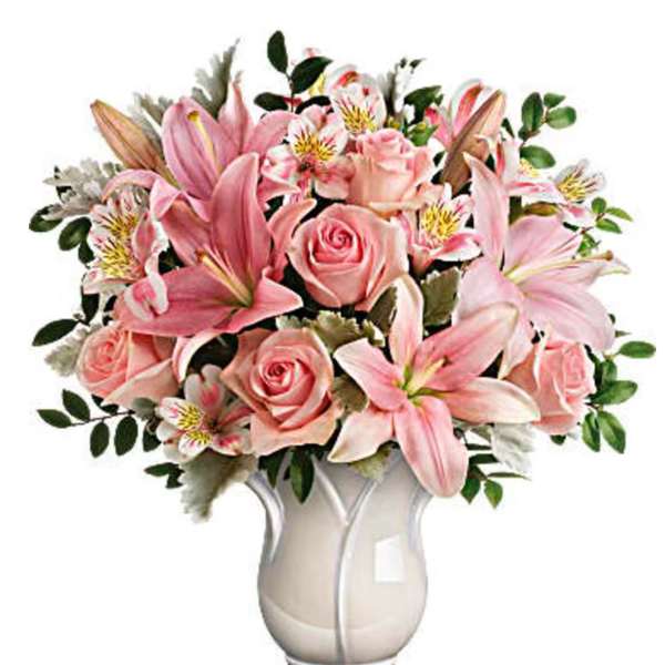 Pink lilies and roses arranged in a white vase