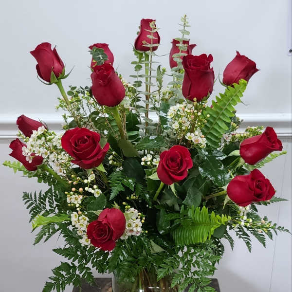 Red roses arranged in a clear glass vase with white filler flowers