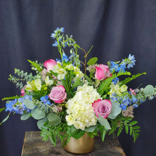 Pink roses and white hydrangea in a gold vase with blue flowers