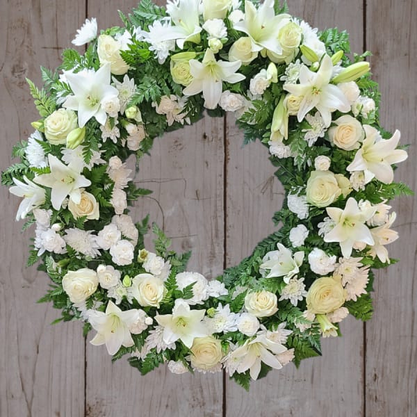 White floral wreath with lilies and roses on a wooden background