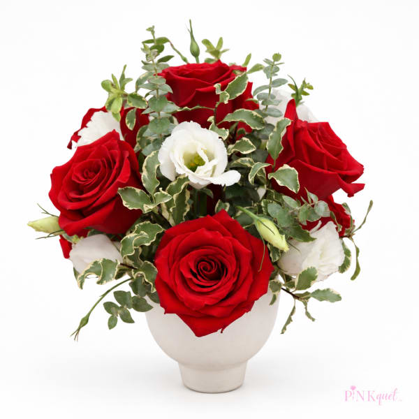 Red roses and white blooms arranged in a white vase