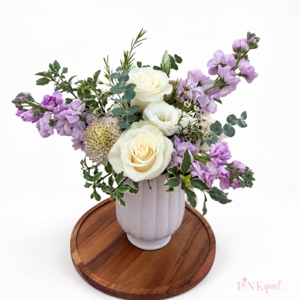 White roses and lavender flowers in a white vase