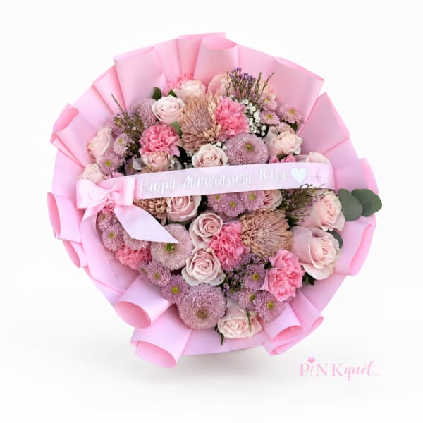 Pink bouquet of roses and mixed blooms wrapped in pastel paper