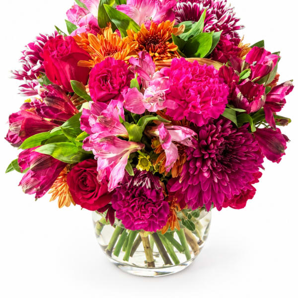 Bright mixed bouquet of pink, orange, and magenta flowers in a clear glass vase