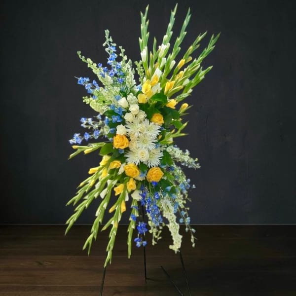 Tall floral standing spray with yellow, white, and blue flowers