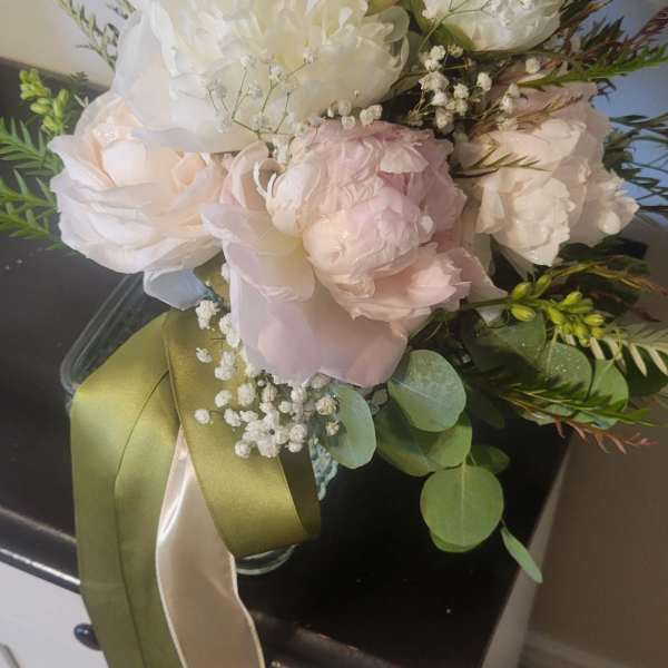 Blush and white bouquet in a glass vase with long ribbon tails