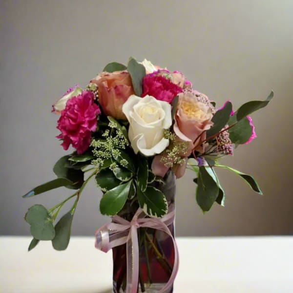 Bouquet of pink and white roses in a glass vase with ribbon