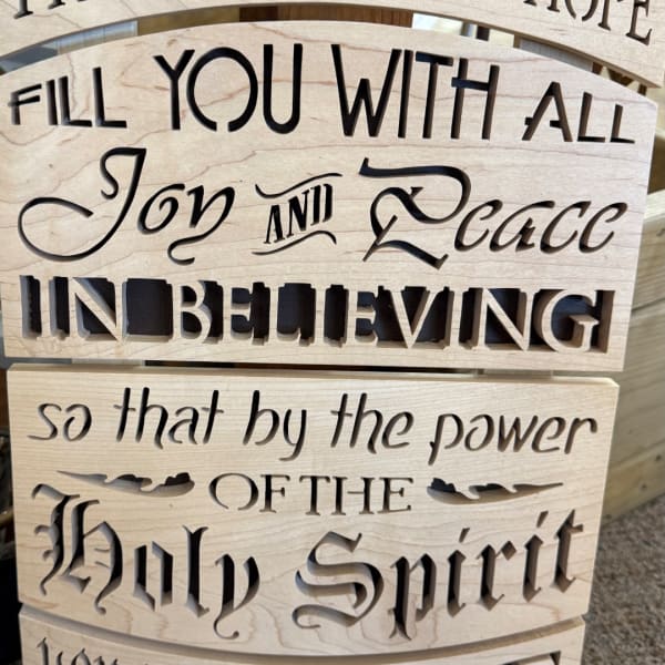 Wooden sign with cutout religious text about filling with peace and the Holy Spirit.