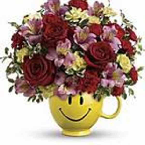 Mixed flower bouquet in a yellow smiley-face mug