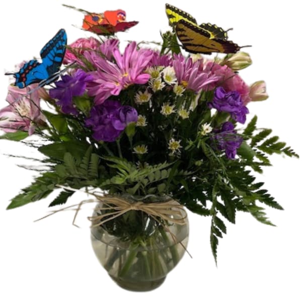 Mixed bouquet of purple and pink flowers in a glass vase with butterfly picks