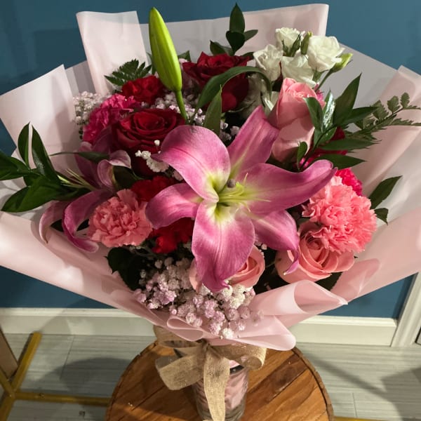 Pink and red mixed bouquet with lilies, roses, and carnations in pink wrap