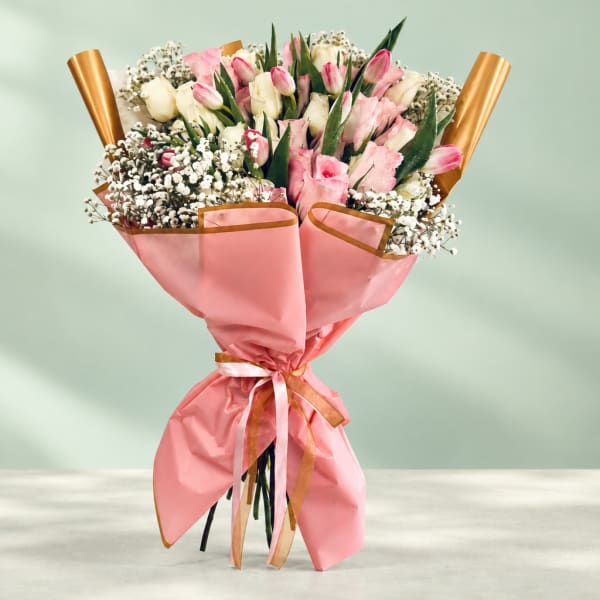Pink and white tulip bouquet wrapped in pink paper with gold ribbon