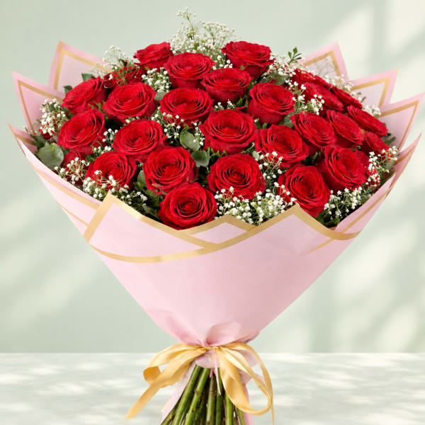 Bouquet of red roses wrapped in pink paper with a gold ribbon