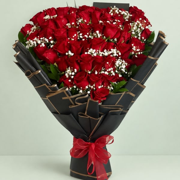 Bouquet of red roses with white baby's breath in black wrapping and a red bow