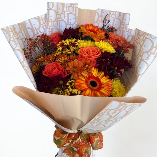 Bouquet of orange, yellow, and burgundy flowers wrapped in patterned paper