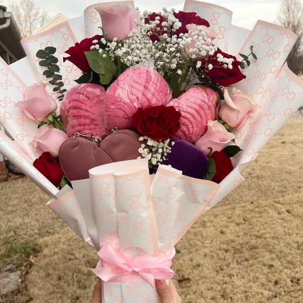 Bouquet of pink and red roses with baby’s breath and heart-shaped gifts