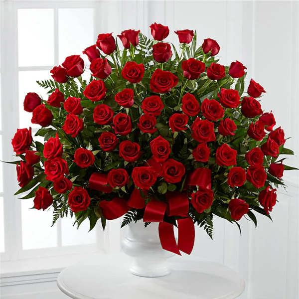 Large bouquet of red roses in a white vase with a red ribbon