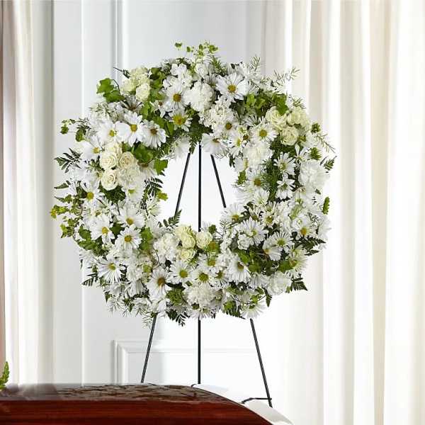 White floral wreath on a black stand