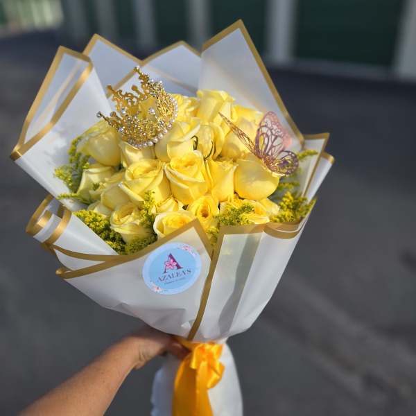 Yellow rose bouquet wrapped in white and gold paper with a decorative crown