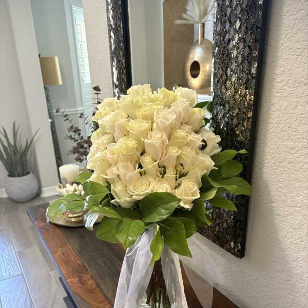 Bouquet of cream roses in a glass vase with a white ribbon