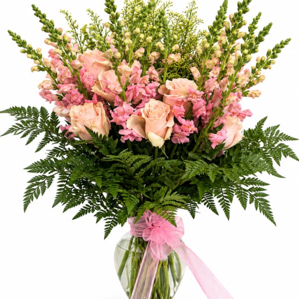 Pink roses and snapdragons in a glass vase with a pink ribbon